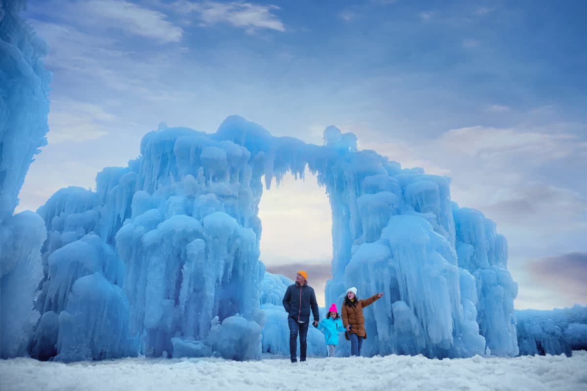 Three people walk in front of a giant ice sculpture in Cripple Creek