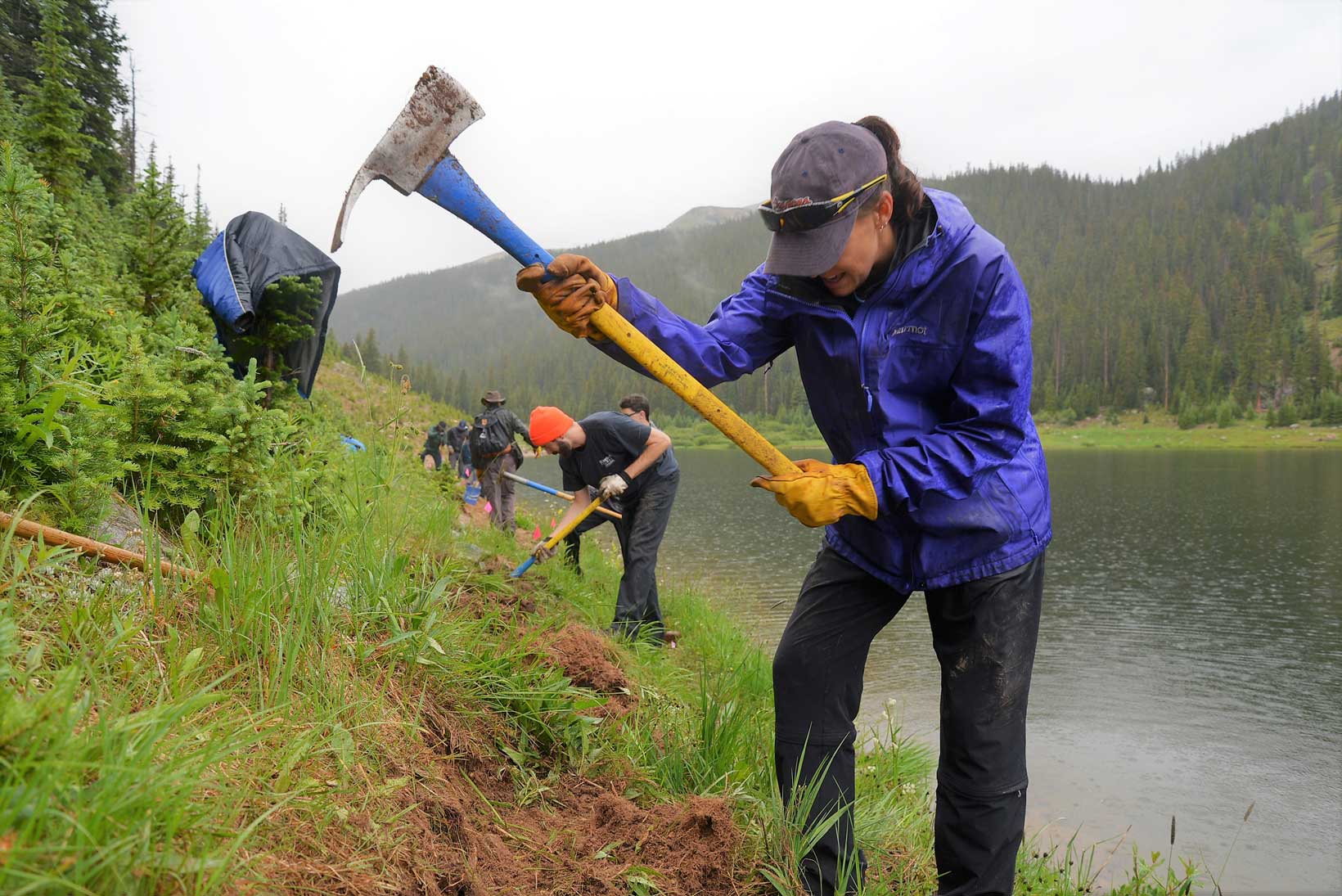 People work on a trail with axes and shovels