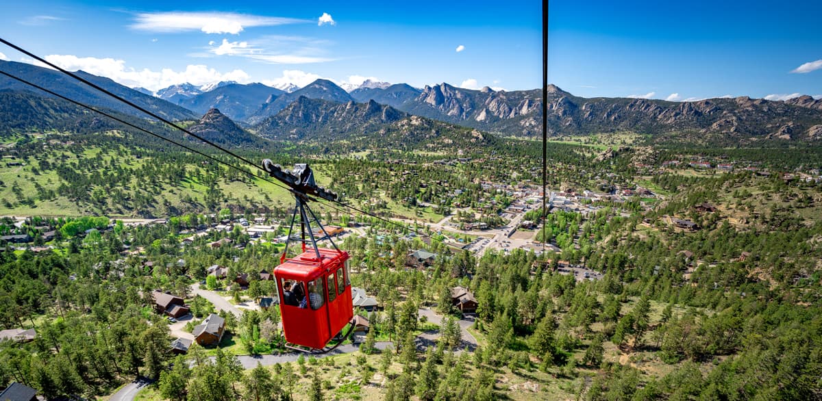 The cherry-red Estes Park Aerial Tram soaring above the treetops.