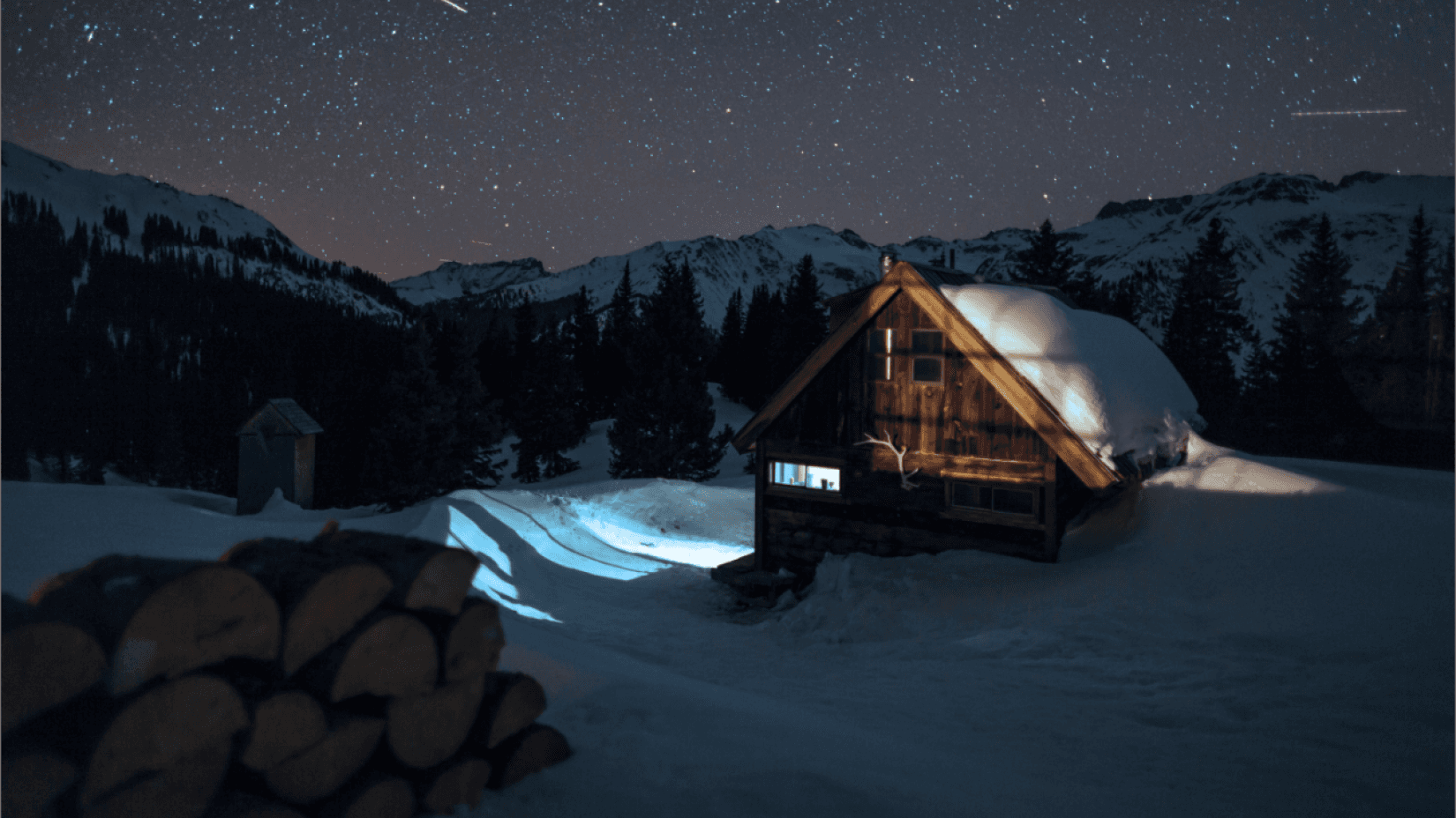 A snow-covered cabin under a starry night sky