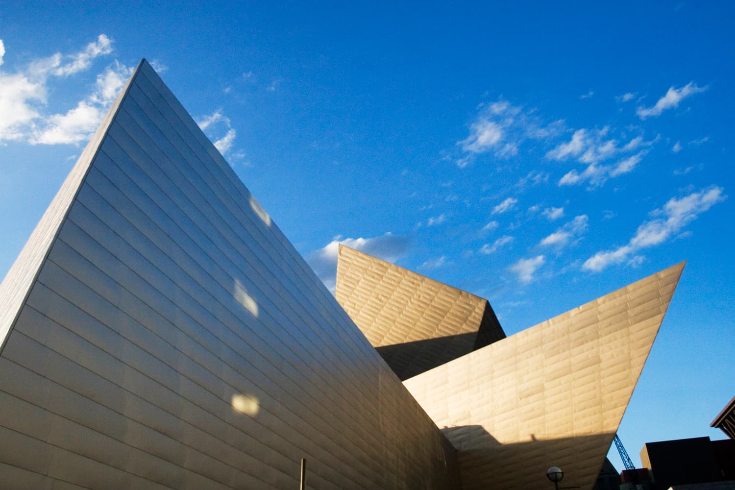 Exterior of Denver Art Museum's abstract building design from below, with a bright blue sky in the background