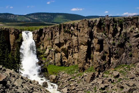 Water rushes down Clear Creek Falls with blue skies in the background