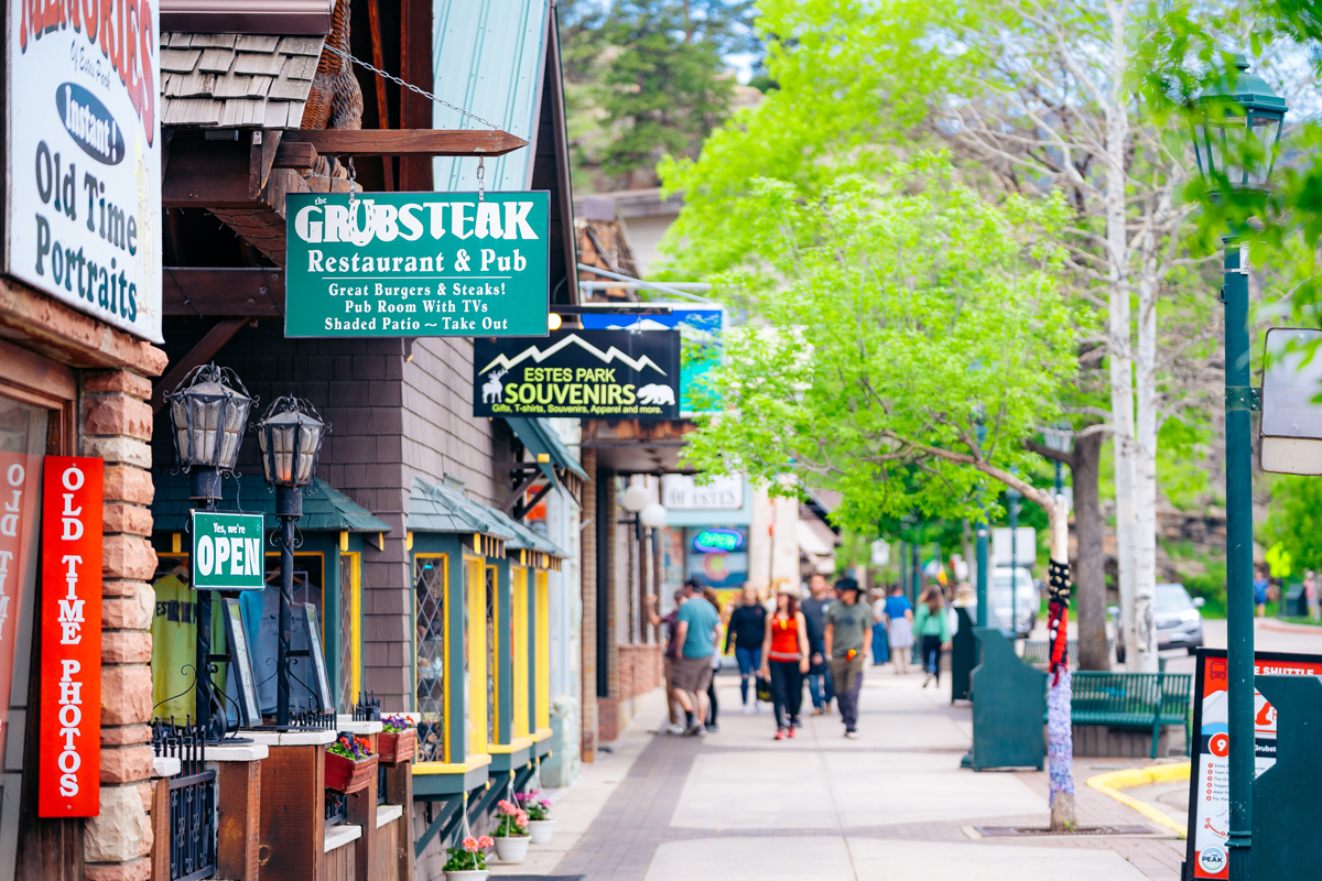 People strolling along the sidewalk which is lined with shops in Estes Park, Colorado.