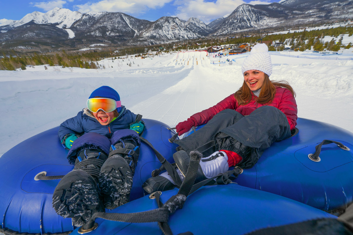 A mom and sun ride a tube down a ski hill in Telluride