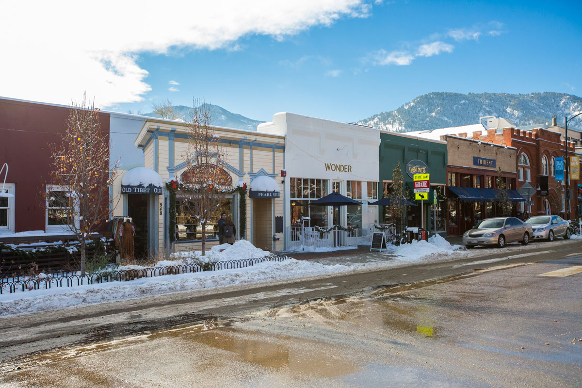 Pearl Street during winter with some melted snow and line of boutiques and shops in Boulder, Colorado.