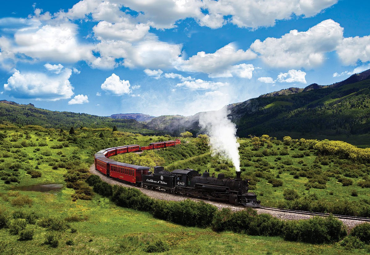 A train winds across tracks in a wide mountain landscape
