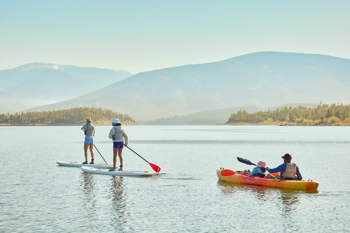 Two people on stand-up paddleboards and one in a kayak on Dillon Reservoir near Frisco, Colorado