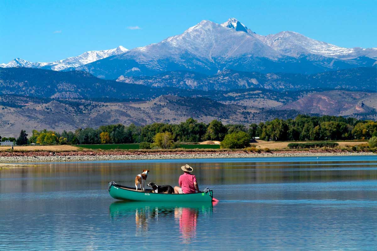 Longs Peak's snow-capped views from a green canoe on the rippling blue surface of McIntosh Lake in Longmont