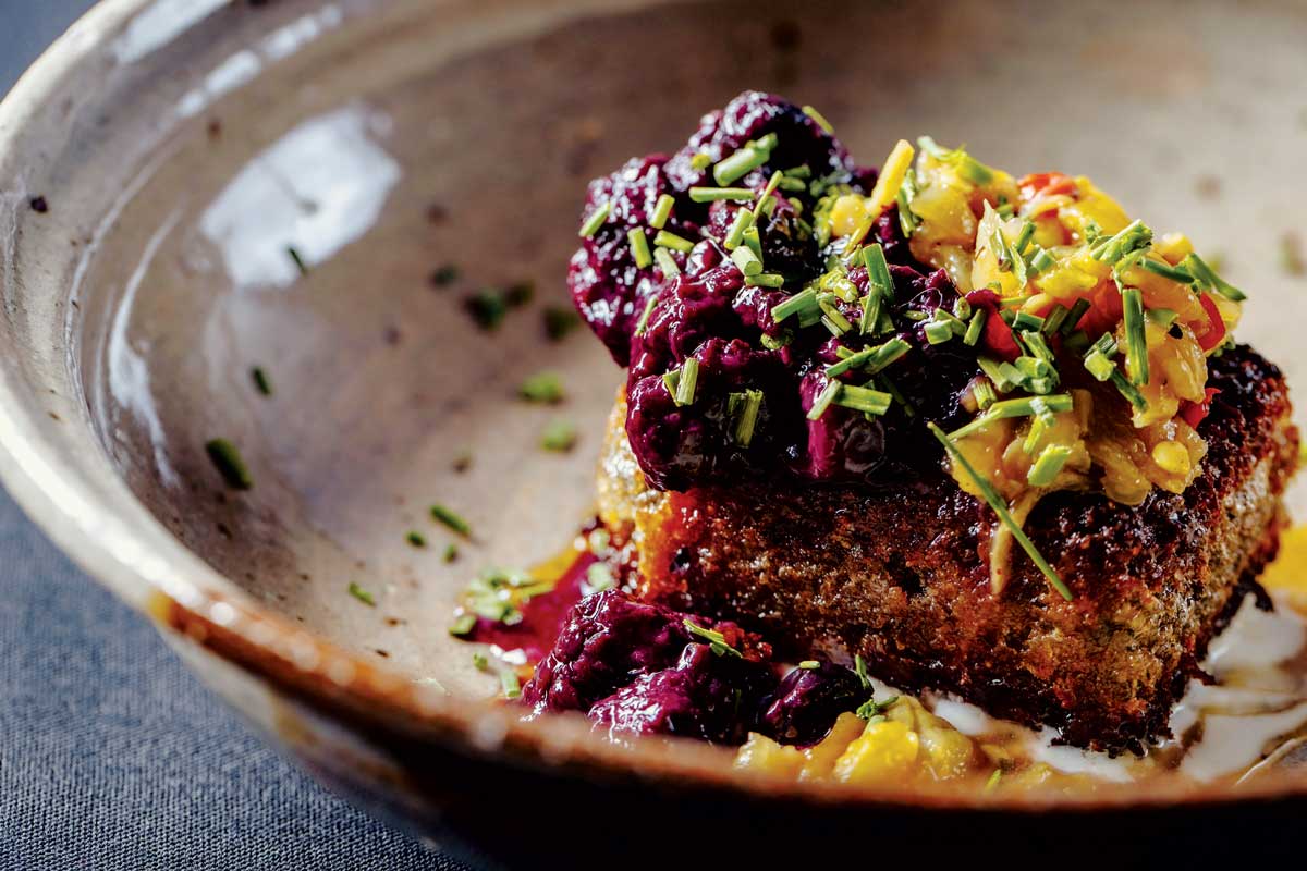 A beige bowl holds fried cornbread beneath bright-yellow squash and purple beets sprinkled with chives at Four, a restaurant by Brother Luck in Colorado Springs, Colorado.
