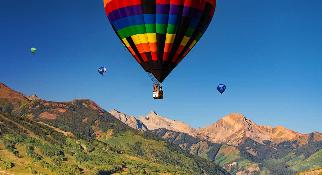 Multicolored balloons above a picturesque mountain background.