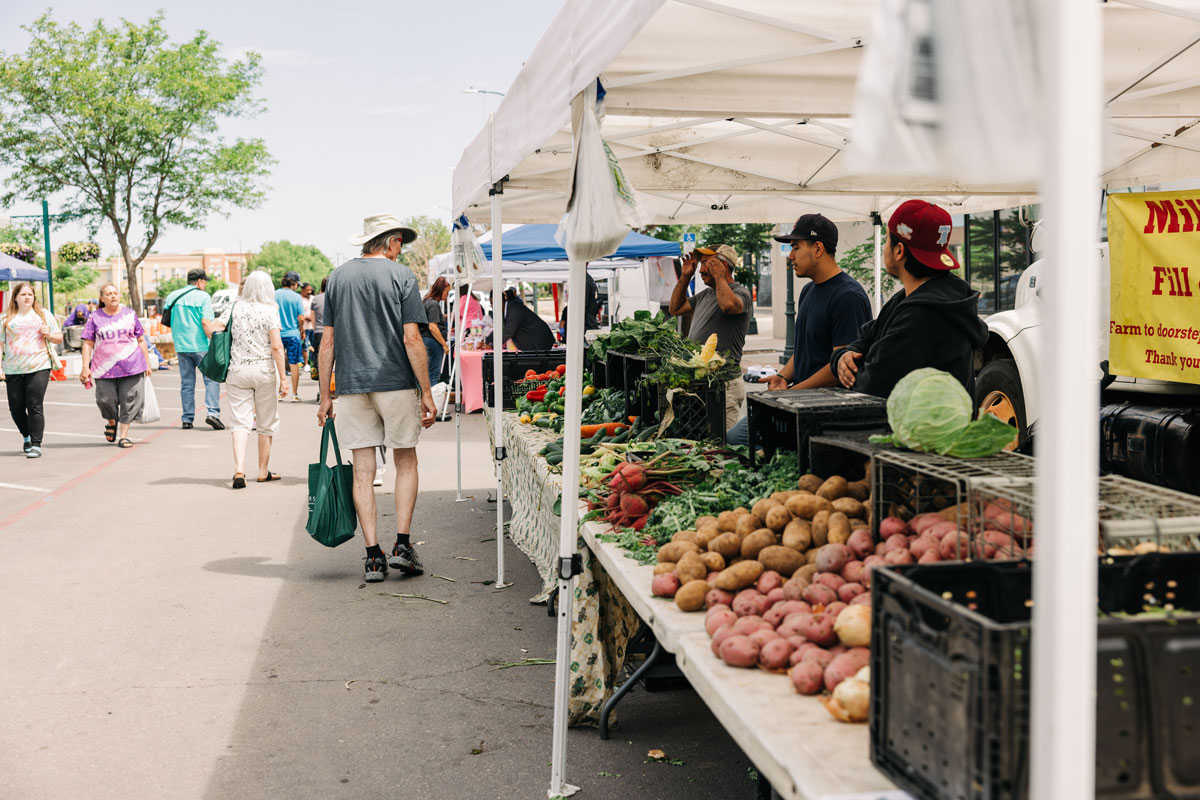 Shoppers and vendors at the Greeley Farmers’ Market browsing fresh produce in Colorado.