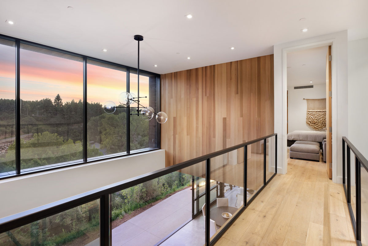 Sunrise appearing from the window with a wooden elevated hallway leading to a bedroom inside a home in Aspen, Colorado.