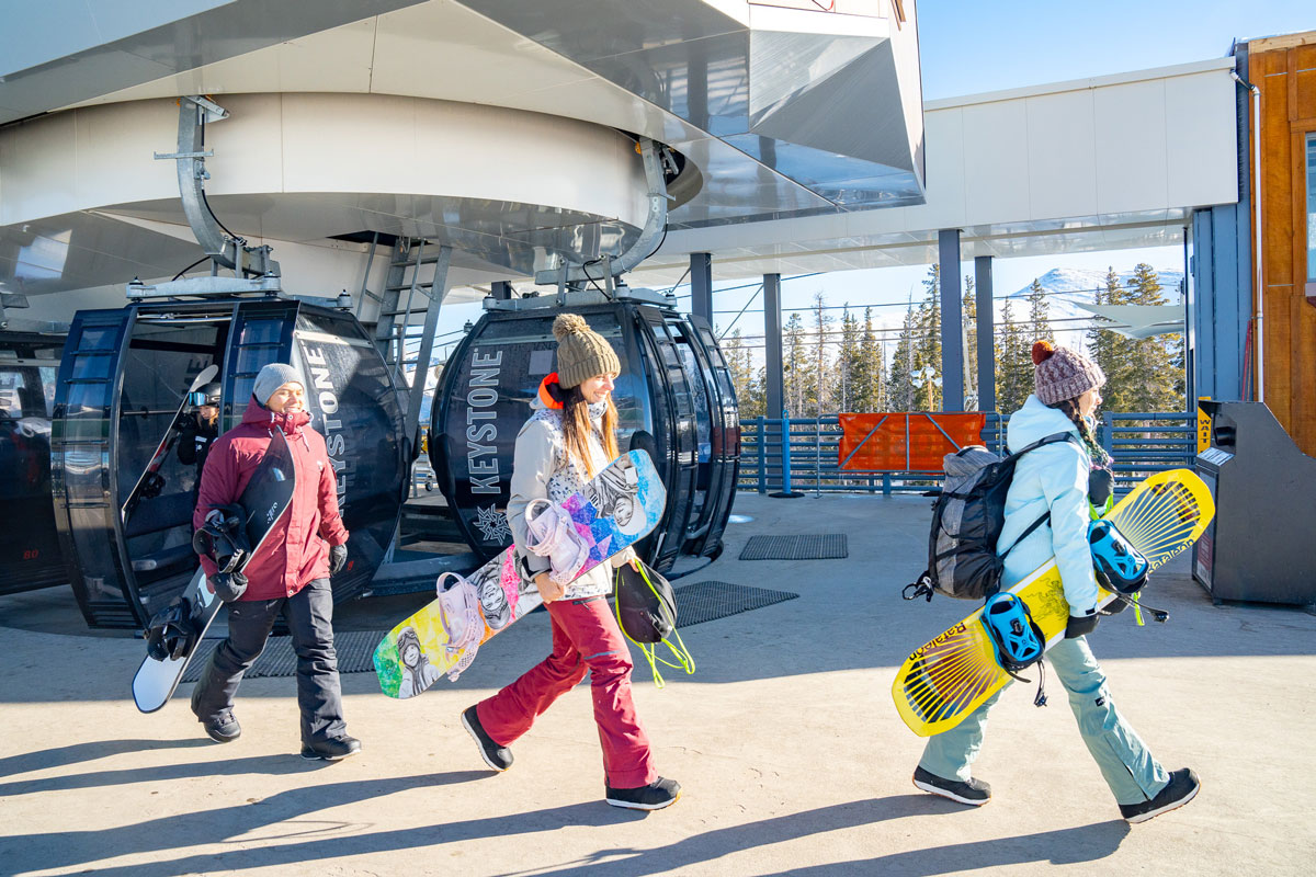 Snowboarders carry their boards by the lift in Keystone