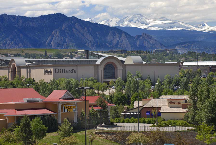 The Dillard's store at Flatiron Crossing mall sits under the Front Range mountains with lots of white clouds above.