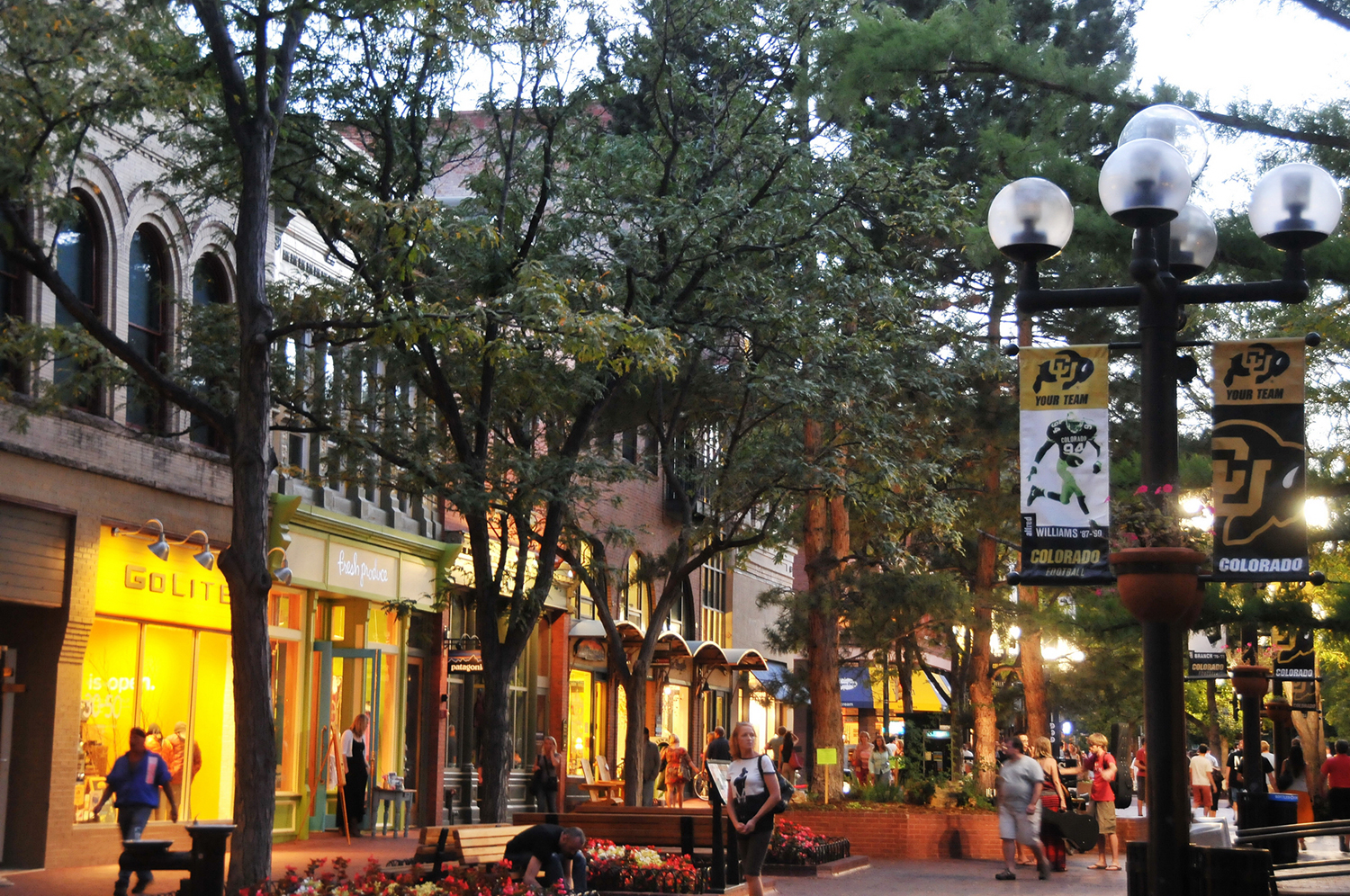 Storefront and street lights begin to turn on as the evening sky sets in over the visitors of Pearl Street Mall in Boulder, Colorado.