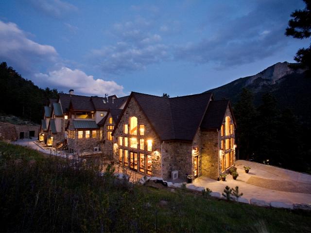 Della Terra Mountain Chateau in Estes Park, a large lodge with massive glowing windows at night. Mountains are in the background