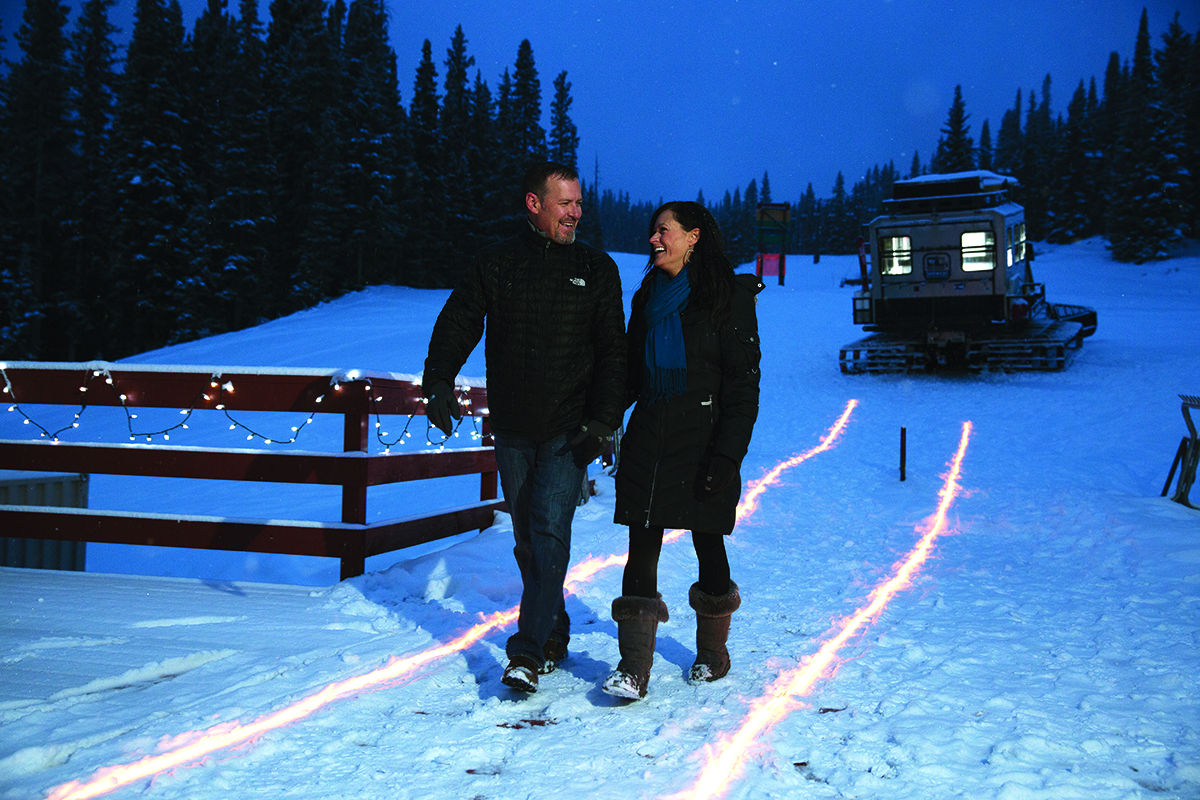 A couple in black clothing walks through away from a snowcat in Colorado.