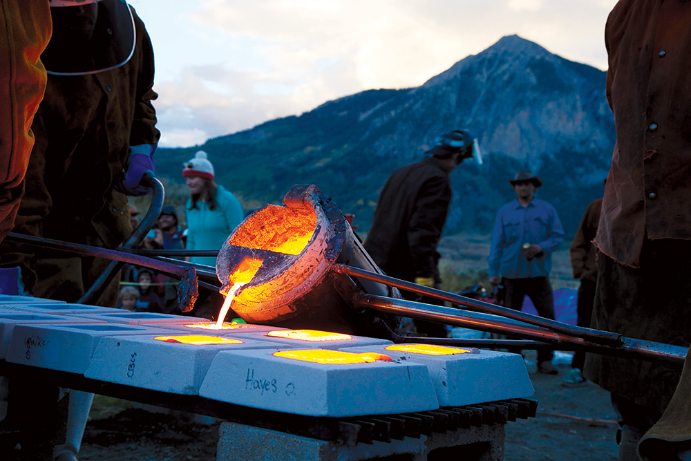 A tool pours a molten liquid into squared, ceramic molds at the Crested Butte's Iron Pour in Colorado.